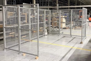 Kovové bezpečnostní oplocení s dveřmi pro oddělení výrobních prostor.