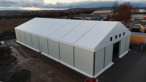 Hala s pevnými boky – bílá střecha, plechové bočnice, logistické využití (letecký pohled)