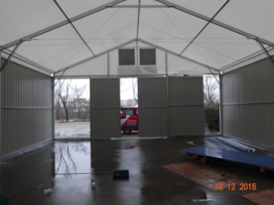 Interiér haly s plechovými stěnami a vraty – pohled na čelní stranu