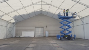 Tent hall extension under construction – interior installation work with a lift