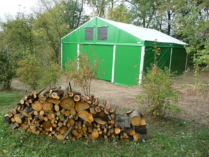 Fabric agricultural hall near woodland for storing wood and materials
