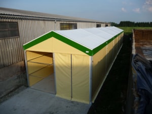 Agricultural tent hall next to a farm building for storage and operational use