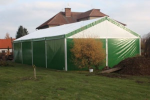 Agricultural tent hall with side cladding on a grassy area near a farm