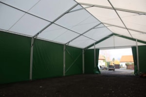 Agricultural tent hall with a drive-through interior and dark side cladding