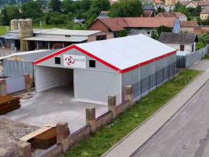 Stanová hala s šedými boky a červeným lemem – průmyslový sklad u komunikace