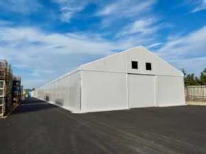 Rozměrná bílá stanová hala na asfaltové ploše – skladovací využití