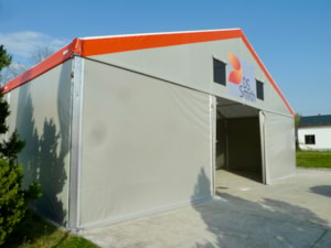 Stanová hala se šedými boky a oranžovým lemem – otevřený vjezd
