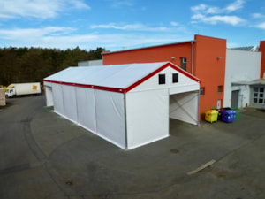 Bílá stanová hala s červeným lemem – pohled shora u budovy