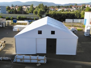 Čelní pohled na stanovou halu se vstupem – sklad v areálu, hory v pozadí