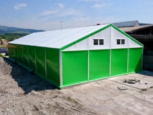 Zelená stanová hala s bílým štítem – skladovací hala u svahu