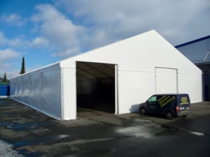 Dlouhá bílá stanová hala s otevřeným vjezdem – sklad v areálu