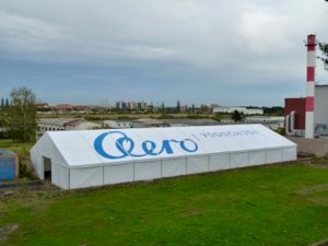 Nízká stanová hala s potiskem na střeše – dlouhý objekt na travnaté ploše